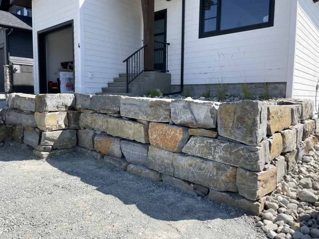 Natural rock retaining wall beside a modern lake home