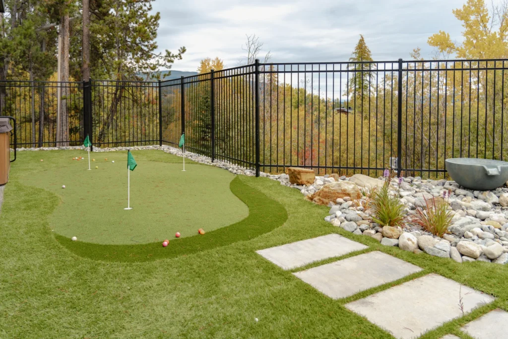 Backyard putting green framed by ornamental fencing