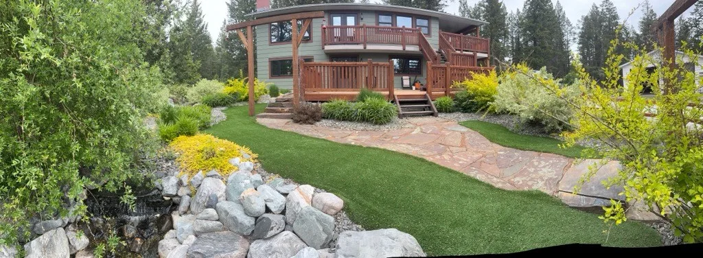 Artificial turf framed by natural planting and river rock