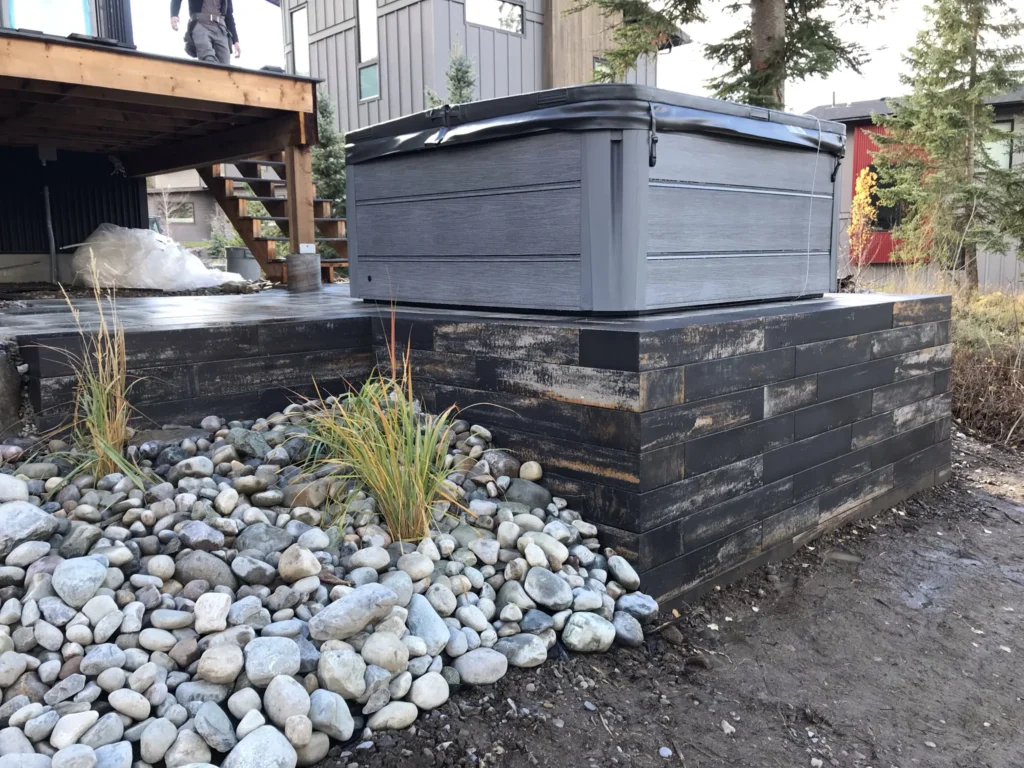Dark retaining wall and round rock detail around the hot tub