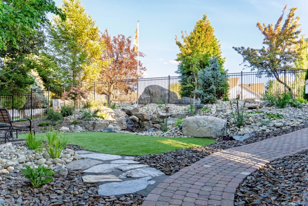 Two-stream pondless water feature set into the grade below ornamental fencing