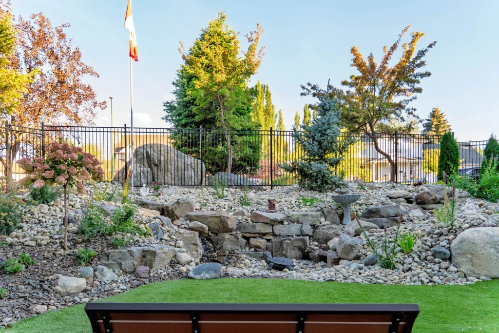 Rock garden slope with stream, bird bath, and a garden bench in the foreground