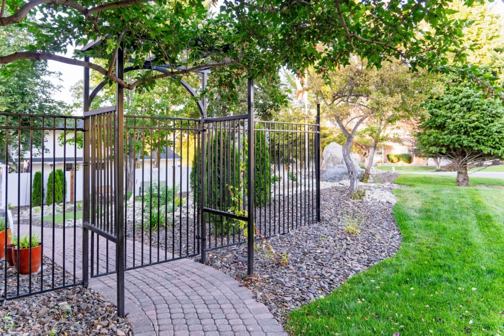 Ornamental fence and arbor with brown shale ground cover and the striated boulder