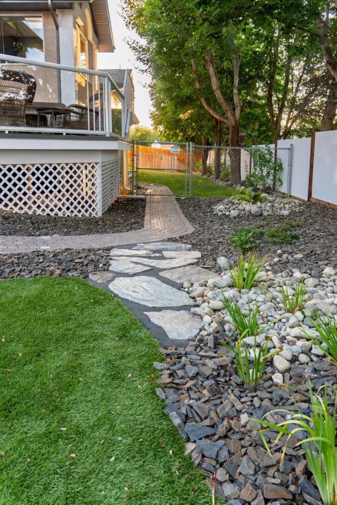 Flagstone stepping stones through river rock and new plantings beside the deck